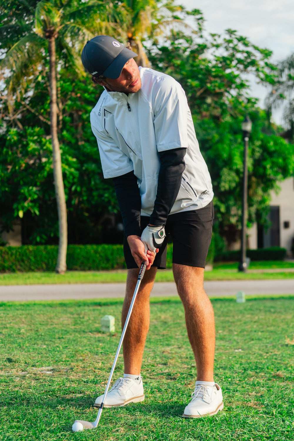 Man preparing for a swing on the golf course wearing Sunice clothing.