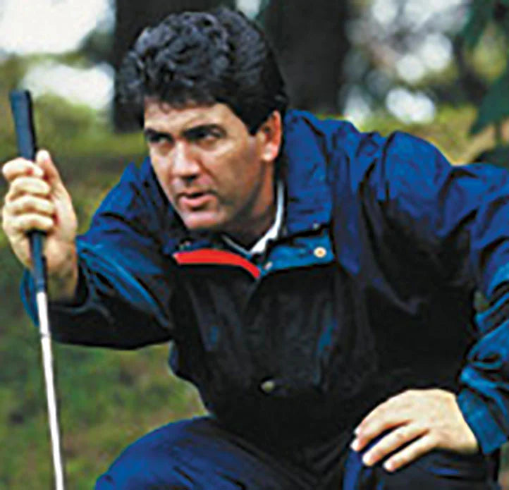 Man in a blue jacket holding a golf club in a natural setting